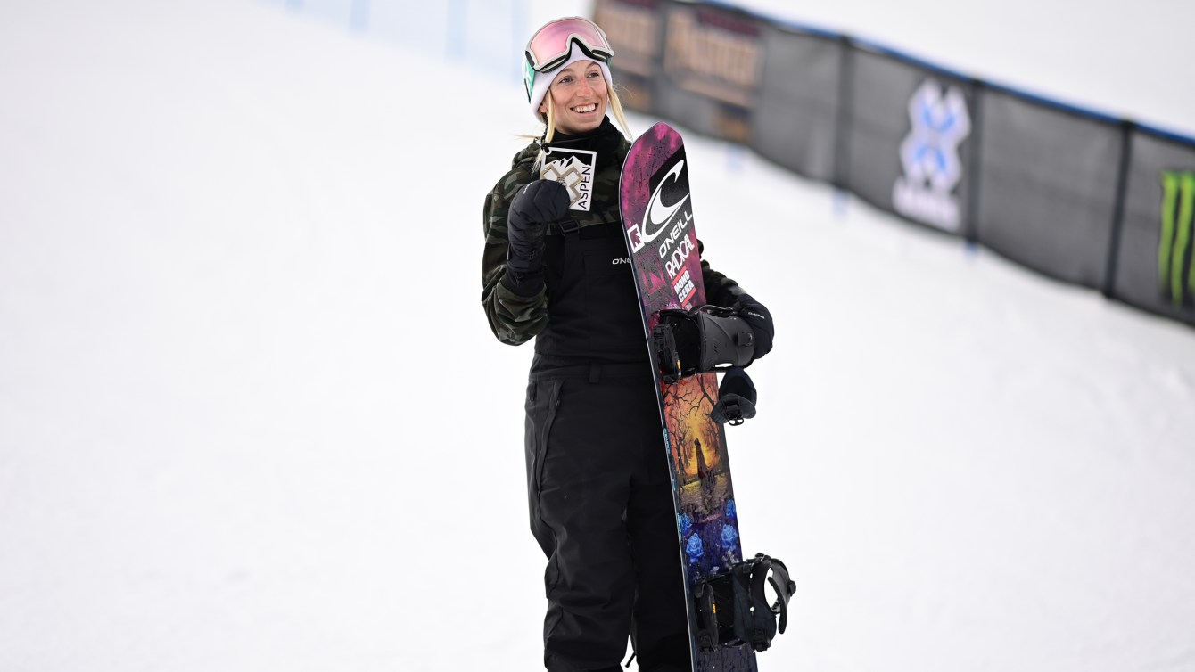 Laurie Blouin holds up her medal and hugs her snowboard at the X Games.