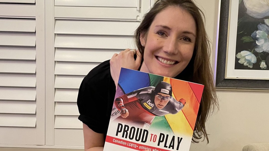 Woman holding a book with the title Proud to Play