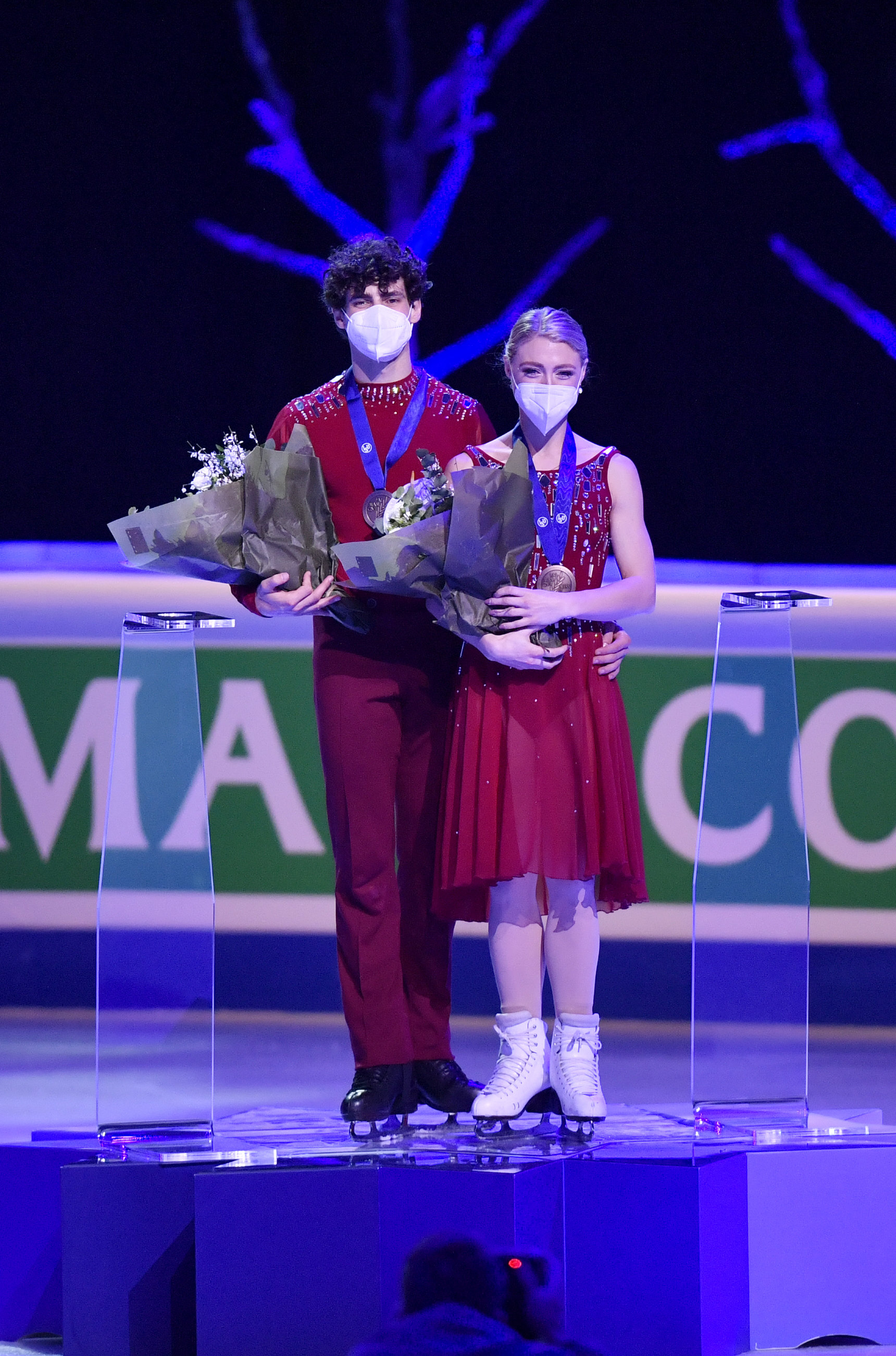 Two figure skaters stand on the podium