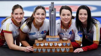 Four curlers pose with the Tournament of Hearts trophy