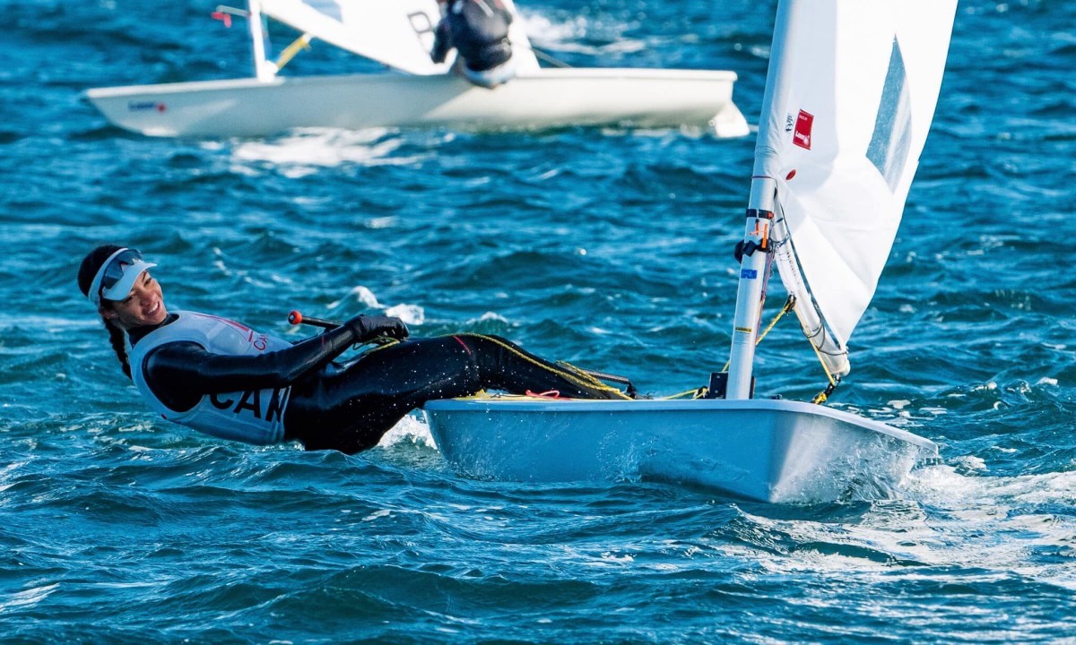 Sarah Douglas leans back over the water while sailing her boat