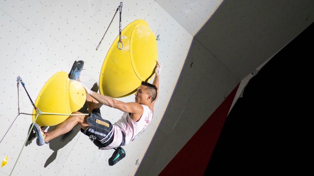 Sean McColl hangs off two handholds during a lead climbing event