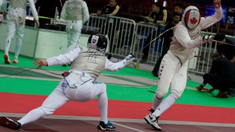 Two masked fencers mid match