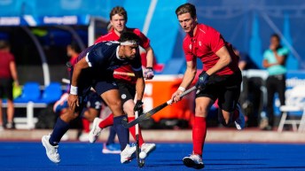 Three field hockey players battle for the ball