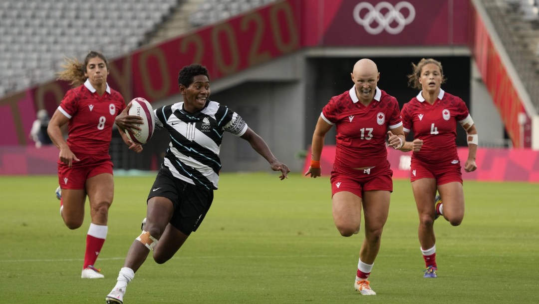 Canadian rugby players chase an opponent carrying a ball