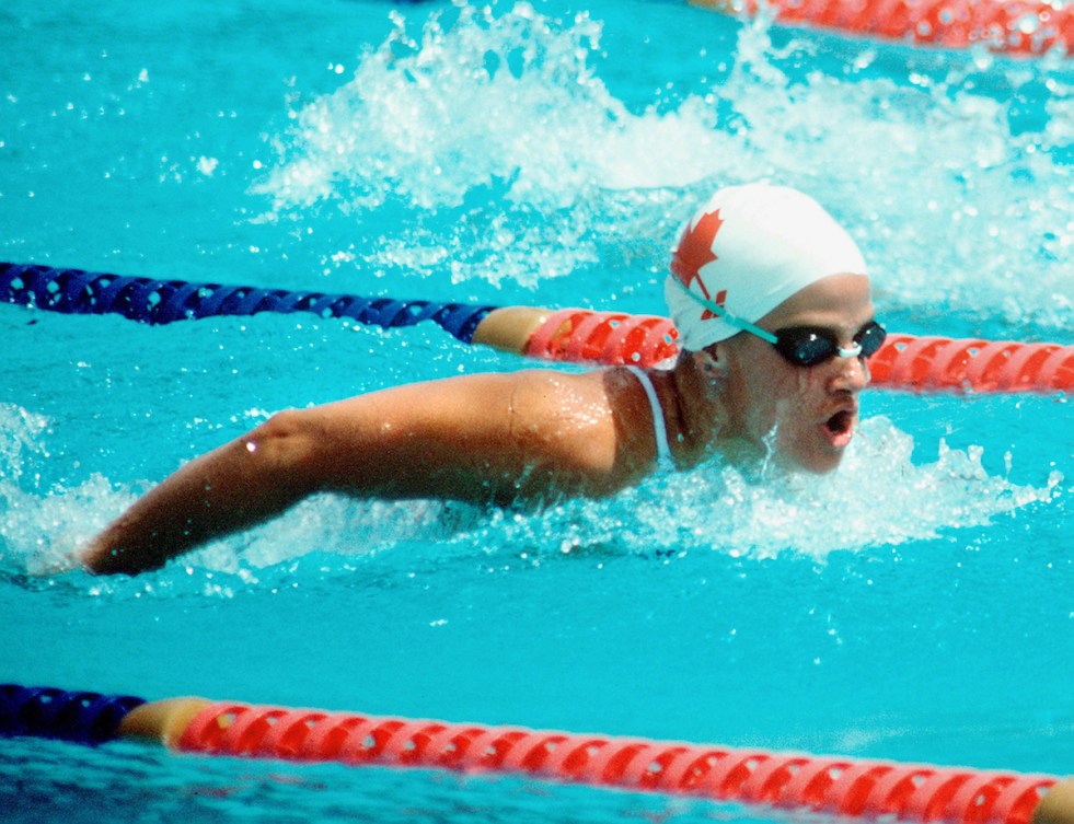 A photo of Nancy Garapick swimming in a red maple leaf swim cap between lane markers.