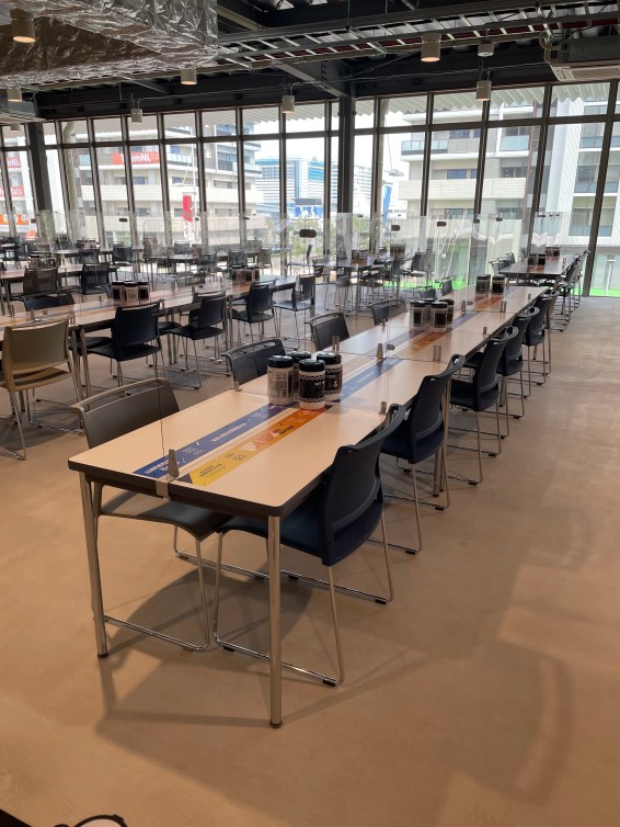 Tables and chairs set up in a dining hall with plexiglass dividers