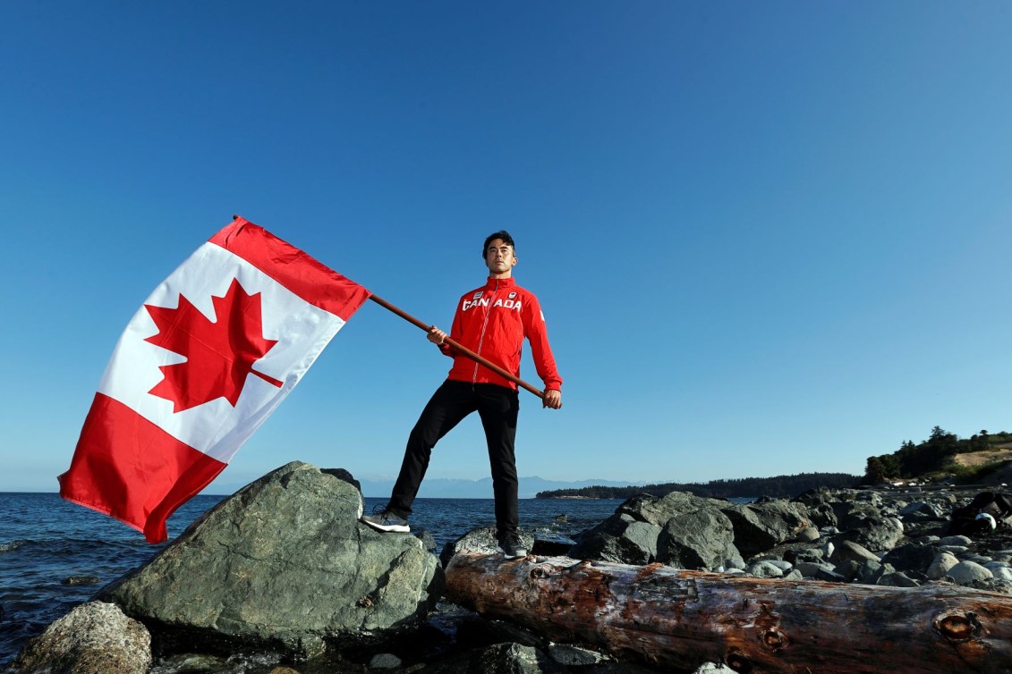 Nathan Hirayama holds Canadian flag by water
