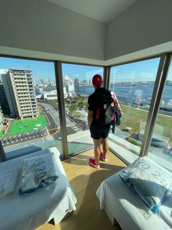 male athlete look out on view of Tokyo from bedroom window in a high rise