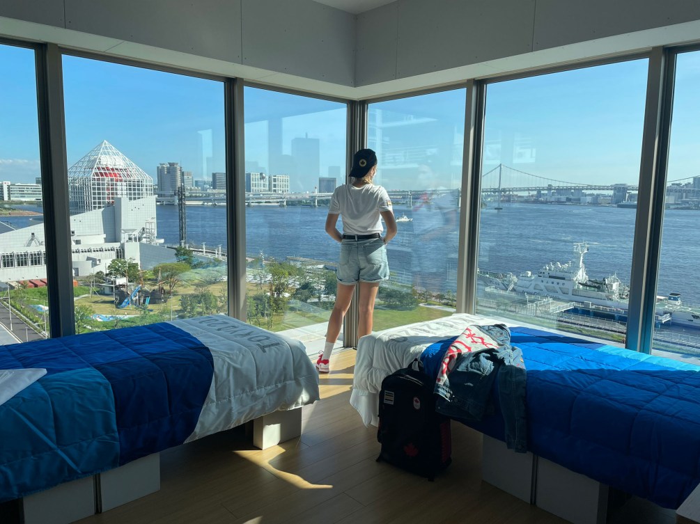 Female athlete checks out the view from her housing window out on the Tokyo scenery