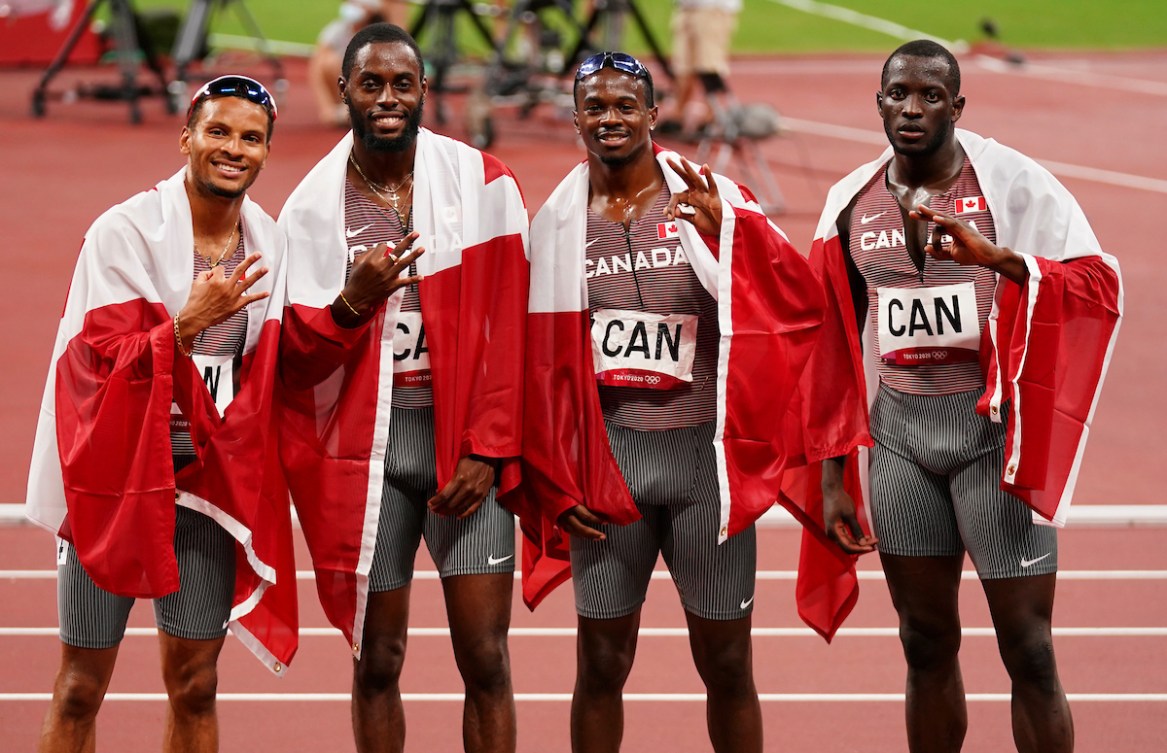 Canada's men's 4x100m relay team poses with the Canadian flag 