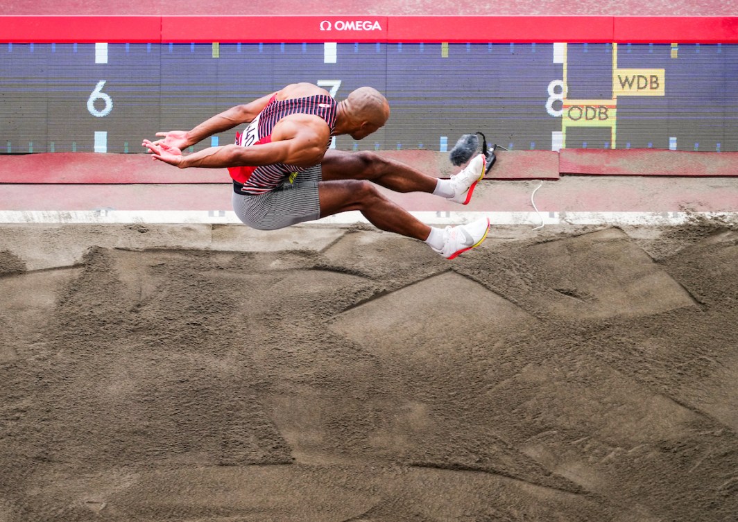 Overhead shot of Damian Warner in air over long jump sand pit 