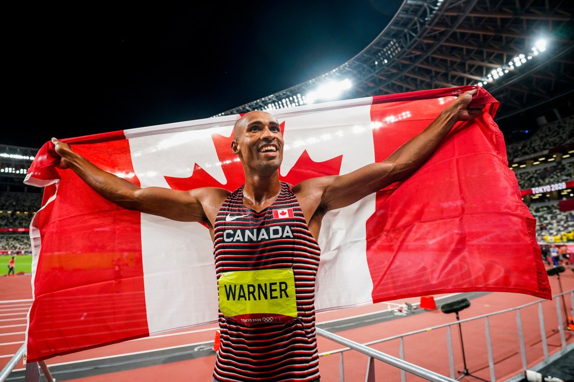 Damian Warner holds Canadian flag over shoulders 