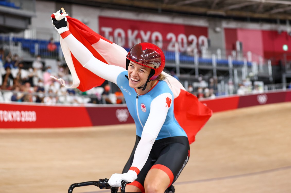 Kelsey Mitchell waves the Canadian flag while doing a victory lap at the velodrome 