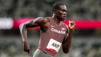 A mid shot of Marco Arop running during a race. His right arm is bent and behind him, his left arm is in front, by his chest.