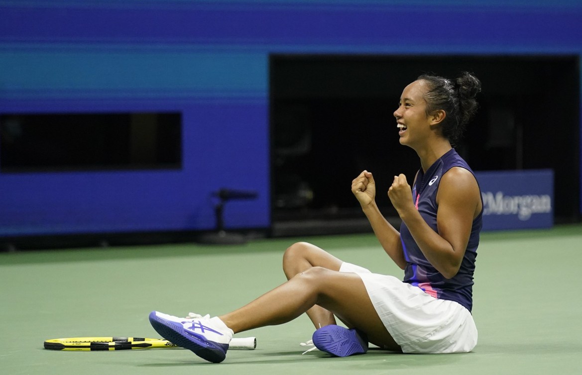 Leylah Fernandez pumps her fists while sitting on the court in celebration after a win