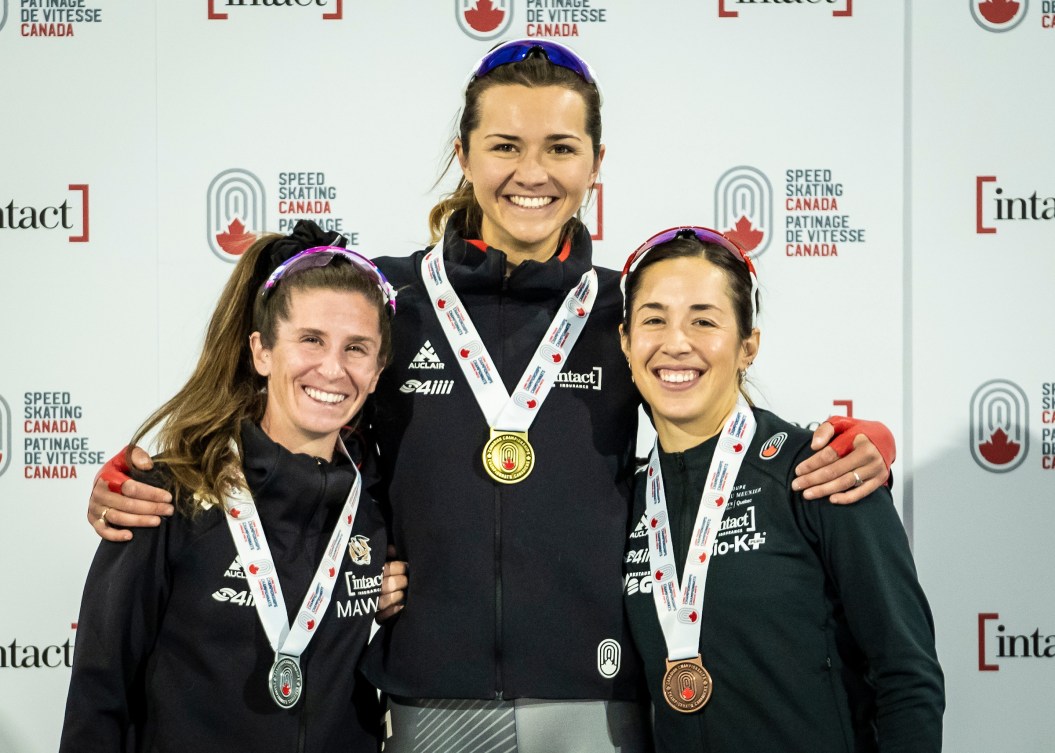 Isabelle Weidemann, Ivanie Blondin and Valerie Maltais stand on the podium with medals around neck 