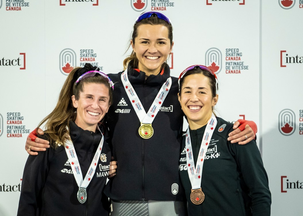 Isabelle Weidemann, Ivanie Blondin and Valerie Maltais stand on the podium with medals around neck