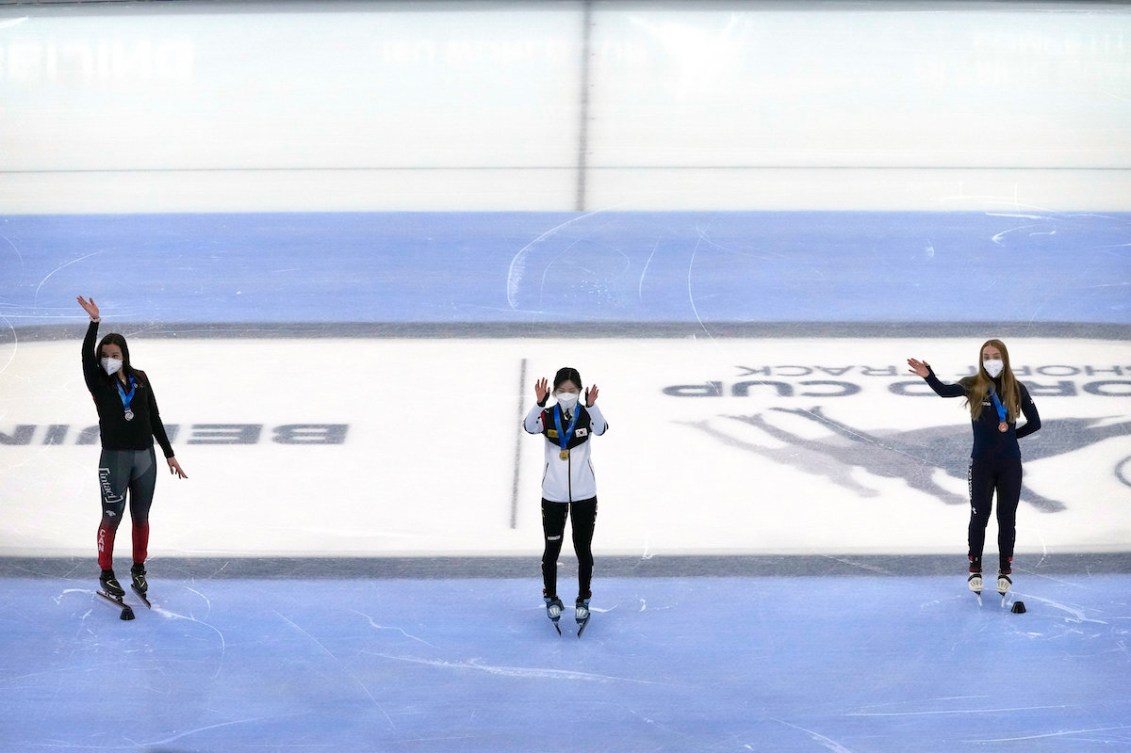 From left, silver medalist Courtney Sarault of Canada, gold medalist Lee Yu-bin of South Korea, and bronze medalist Kristen Santos of the United States wave during the medal ceremony for women's 1500m at the ISU World Cup Short Track speed skating competition, a test event for the 2022 Winter Olympics, at the Capital Indoor Stadium in Beijing, Saturday, Oct. 23, 2021. (AP Photo/Mark Schiefelbein)