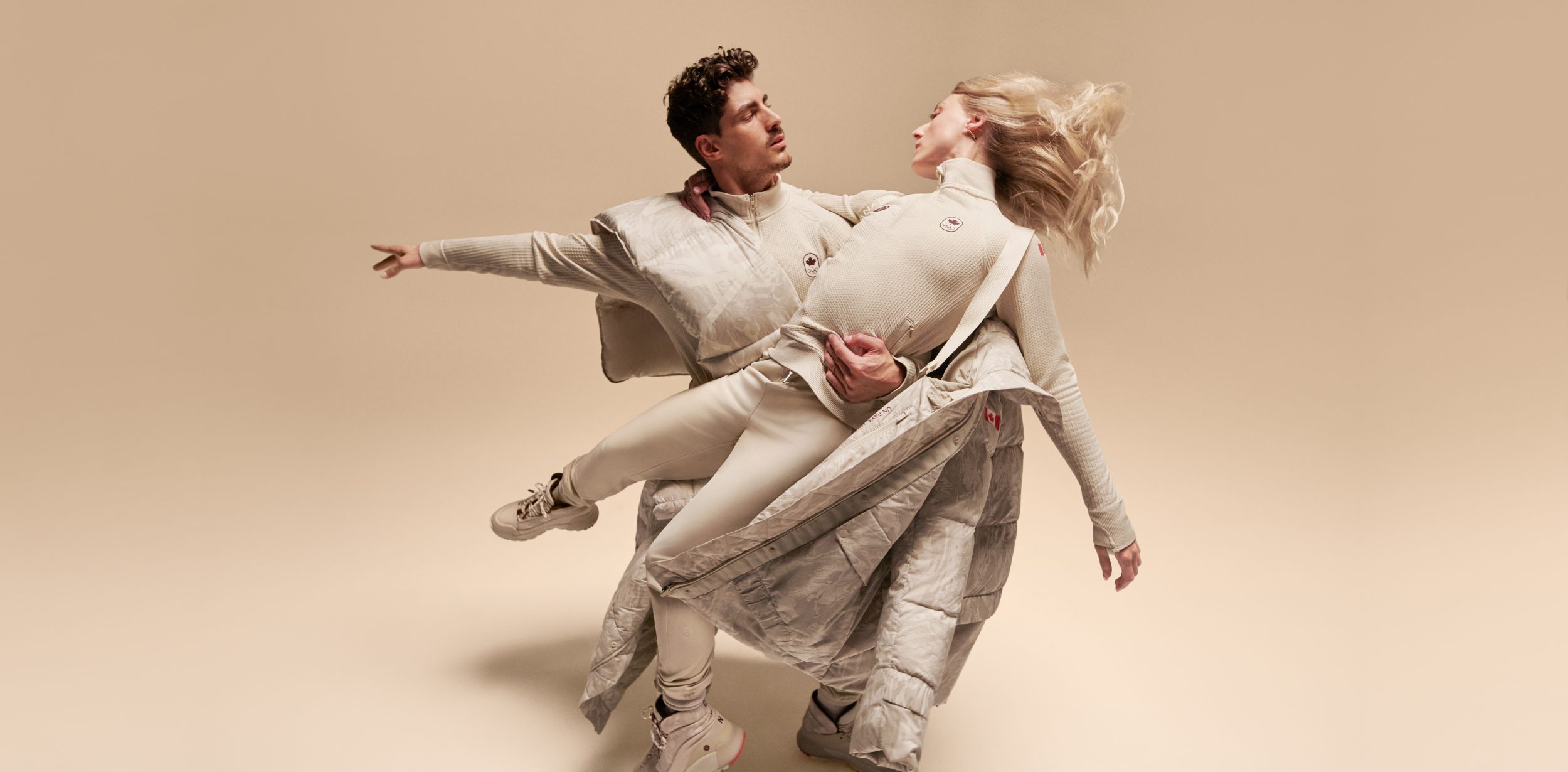 Piper Gilles and Paul Poirier perform a lift while wearing white pants and tops