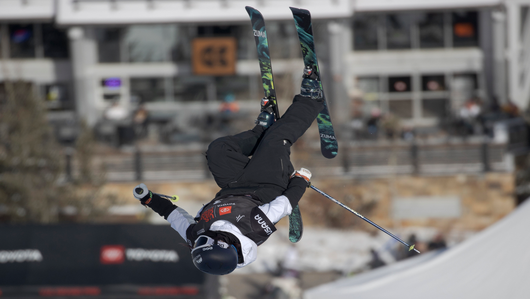 Freestyle skier upside down in the air during a competition.