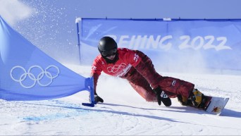 Arnaud Gaudet carves an edge as he snowboards around a gate in a PGS race