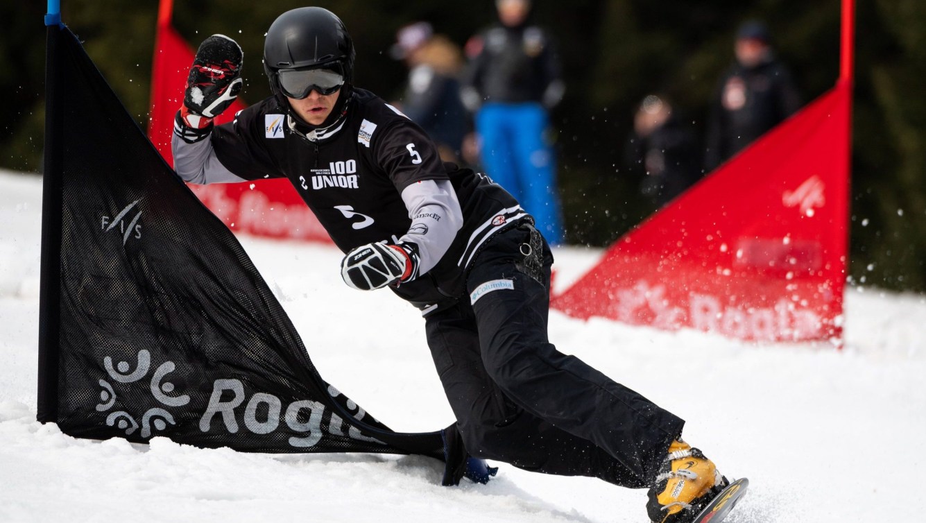 Arnaud Gaudet snowboards past a gate in a race