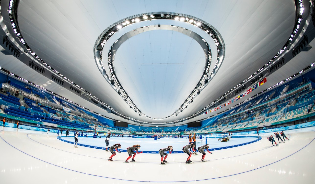 Wide shot of Canadian speed skaters rounding the ice 