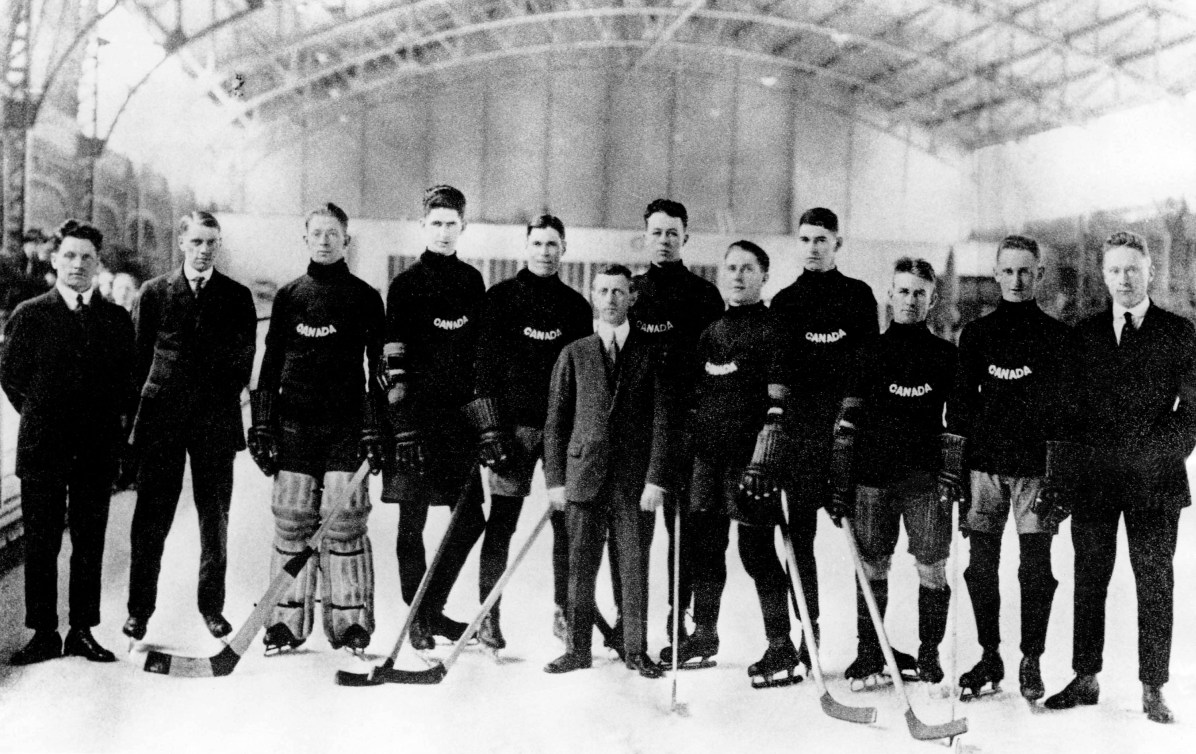 The roster from Team Canada's ice hockey team pose for the camera while standing on ice