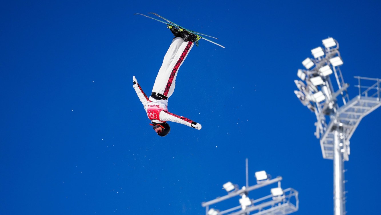 Marion Thenault flips upside down in the sky while performing an aerial trick