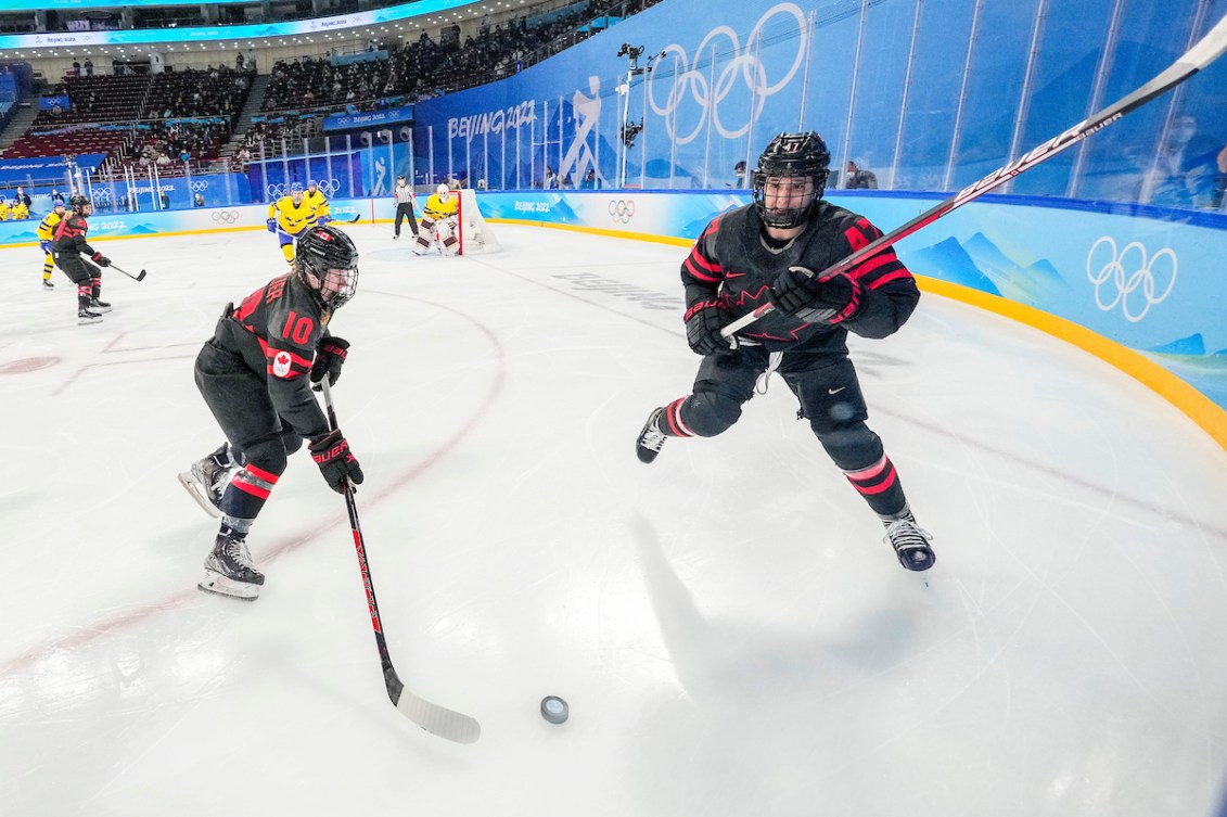 Sarah Fillier #10 of Team Canada plays the puck as Jamie Lee Rattray #47 skates against Sweden