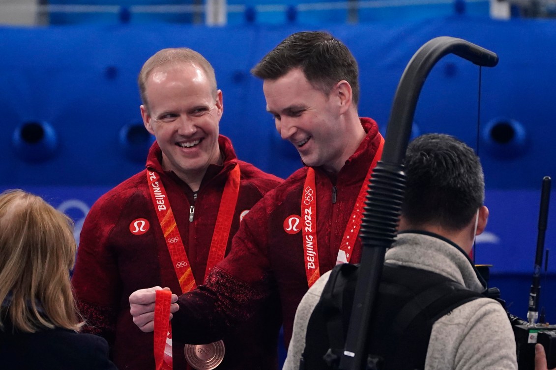 Mark Nichols looks at Brad Gushue as he picks up his bronze medal 