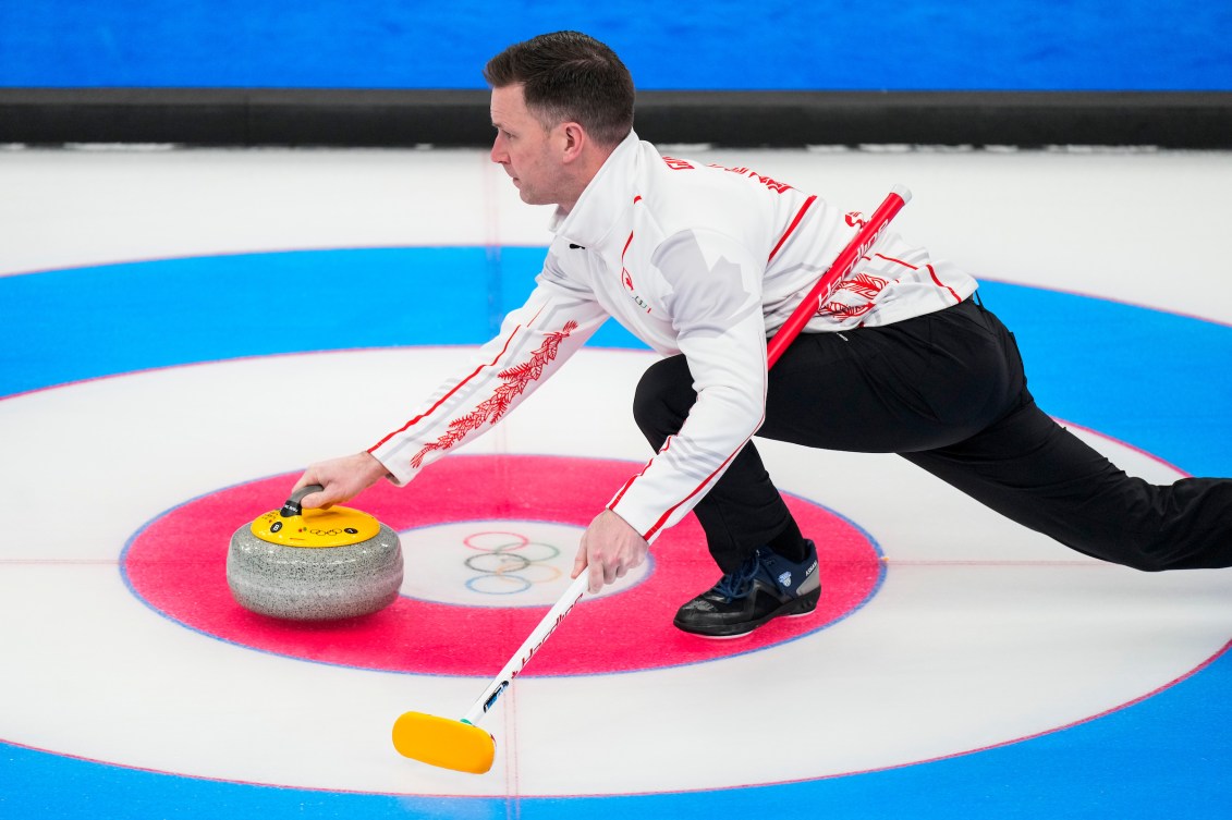 Side angle of Brad Gushue throwing a stone