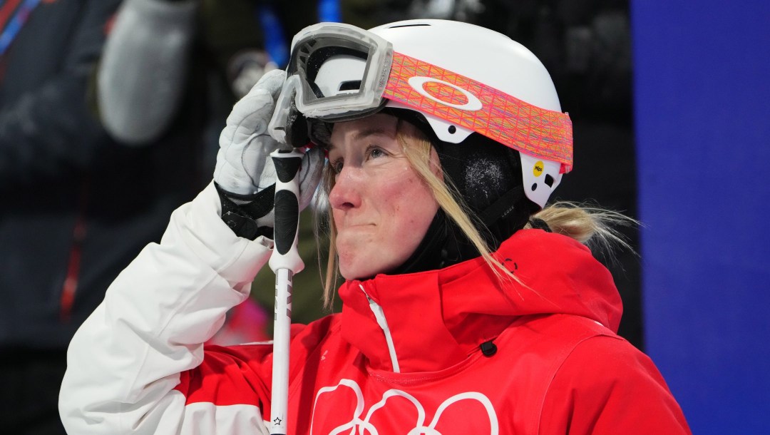 Skiier woman pulling her goggles up as she looks to teh left of the camera.