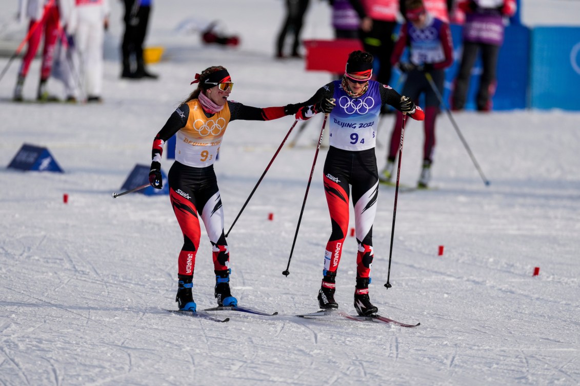 Two cross country skiers make a handoff during a relay 