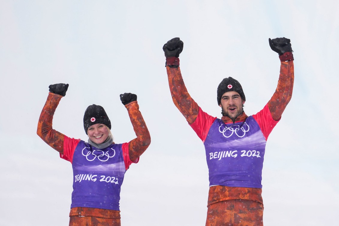 Eliot Grondin and Meryeta O'Dine raise their arms on the podium