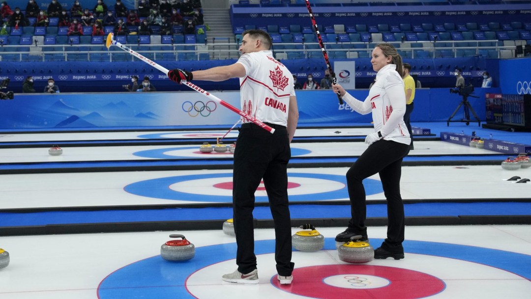 Rachel Homan and John Morris lift their brooms to wave to people