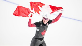 Ivanie Blondin holds the Canadian flag above her head on a victory lap