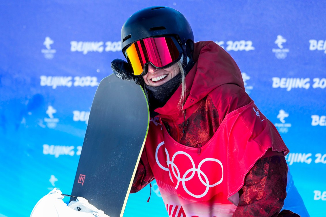 Laurie Blouin smiles while leaning on her board as she waits her score