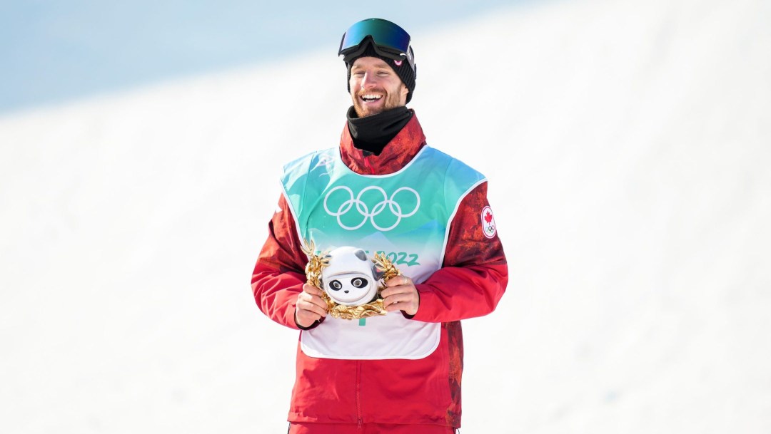 Max Parrot smiles on the podium while holding the mascot toy