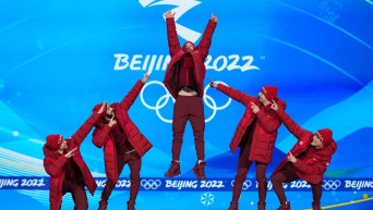 Charles Hamelin jumps on the podium while his teammates point at him