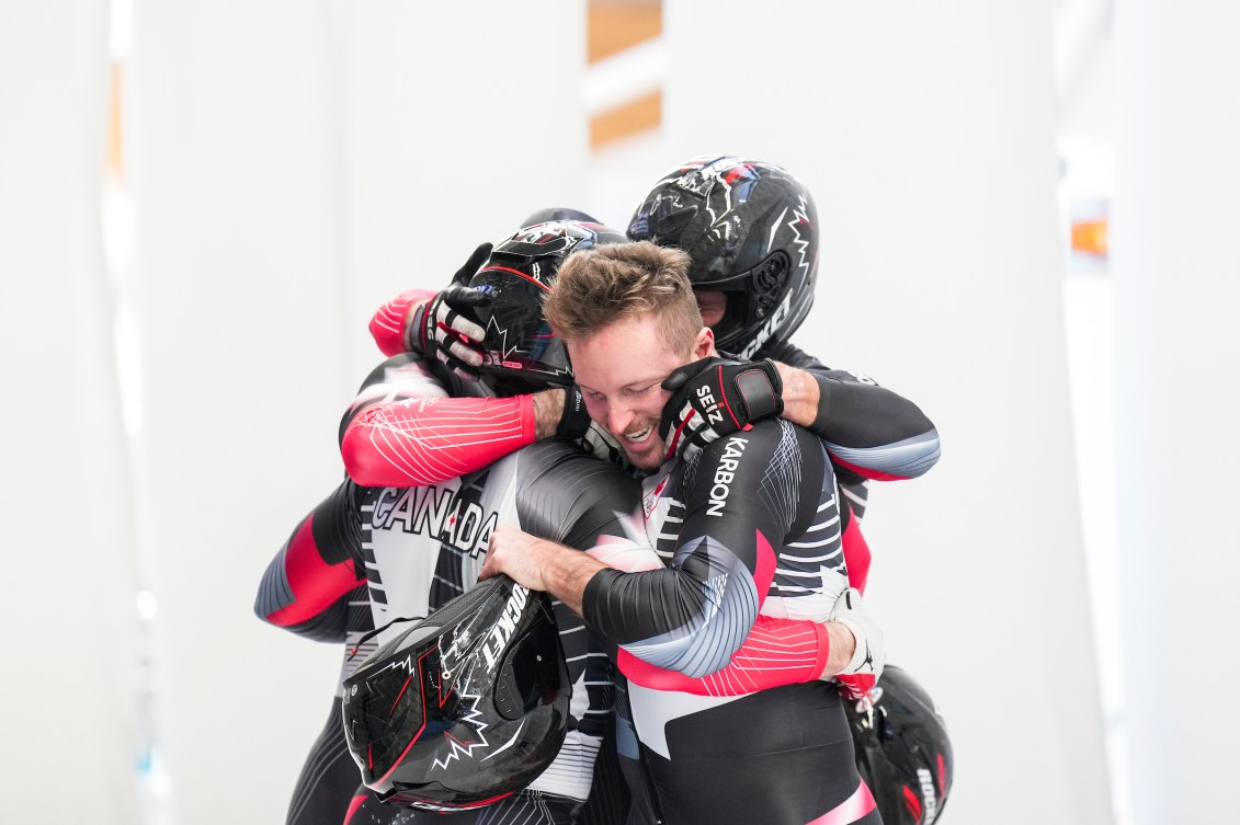 Four bobsledders hug after winning a medal