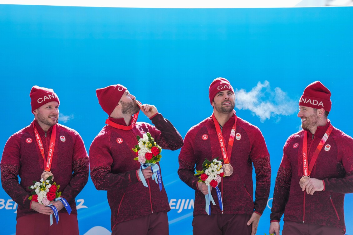 Ryan Sommer kisses his bronze medal as his teammates look on