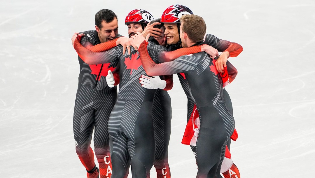 Men's 5000m relay team hugs after winning gold