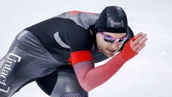 A speed skater keeps a low centre of gravity as he turns a corner towards a straight-away