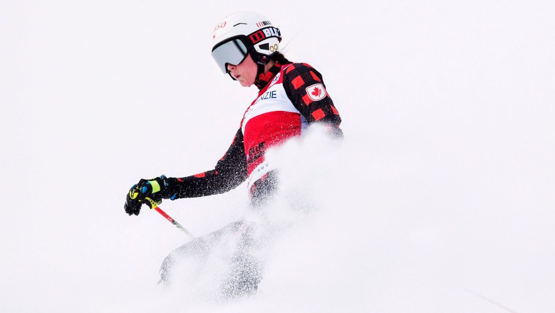 A member of Team Canada stops on the hill with a cloud of snow surrounding her