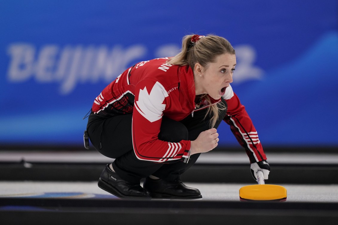 Jocelyn Peterman yells at her teammates while crouching on the ice after throwing her stone
