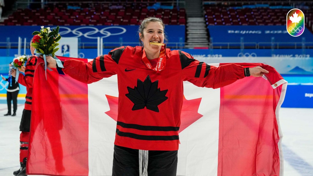Jamie Lee Rattray bites her medal with the Canada flag draped behind her