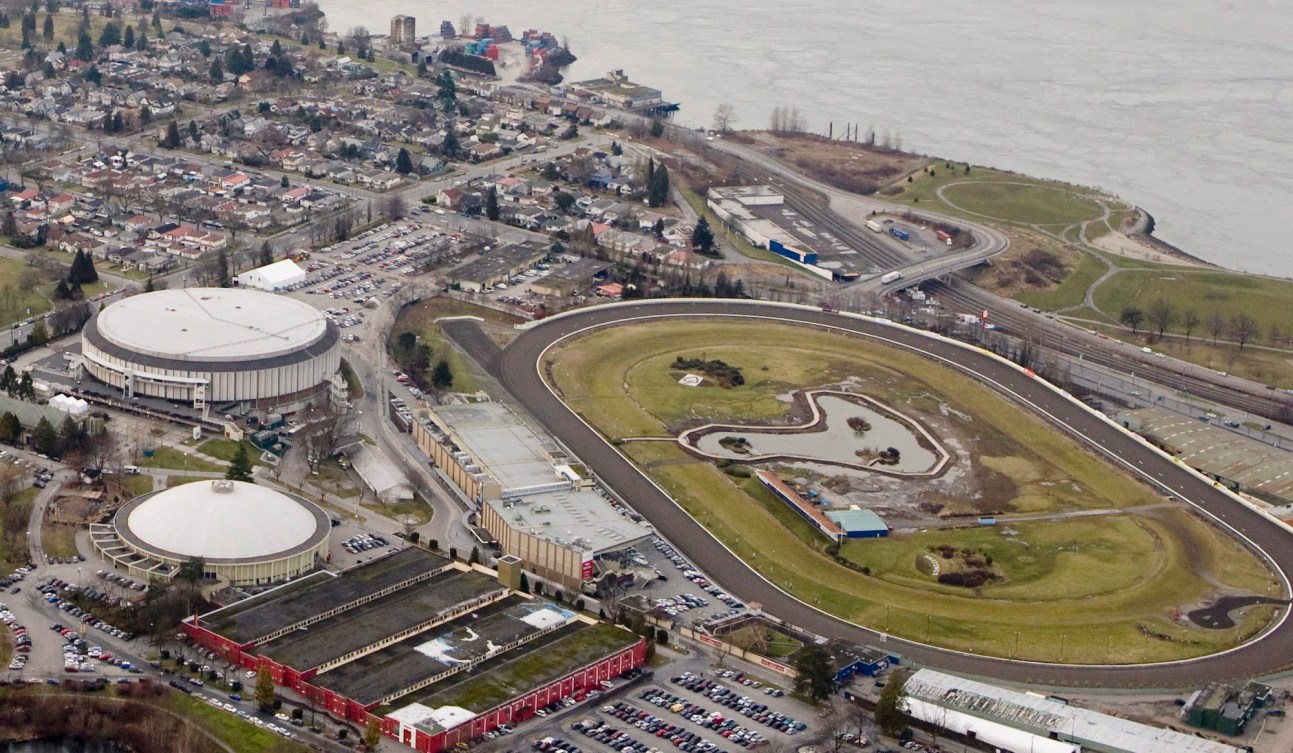 Aerial shot of a race track on the right and two sports buildings on the left