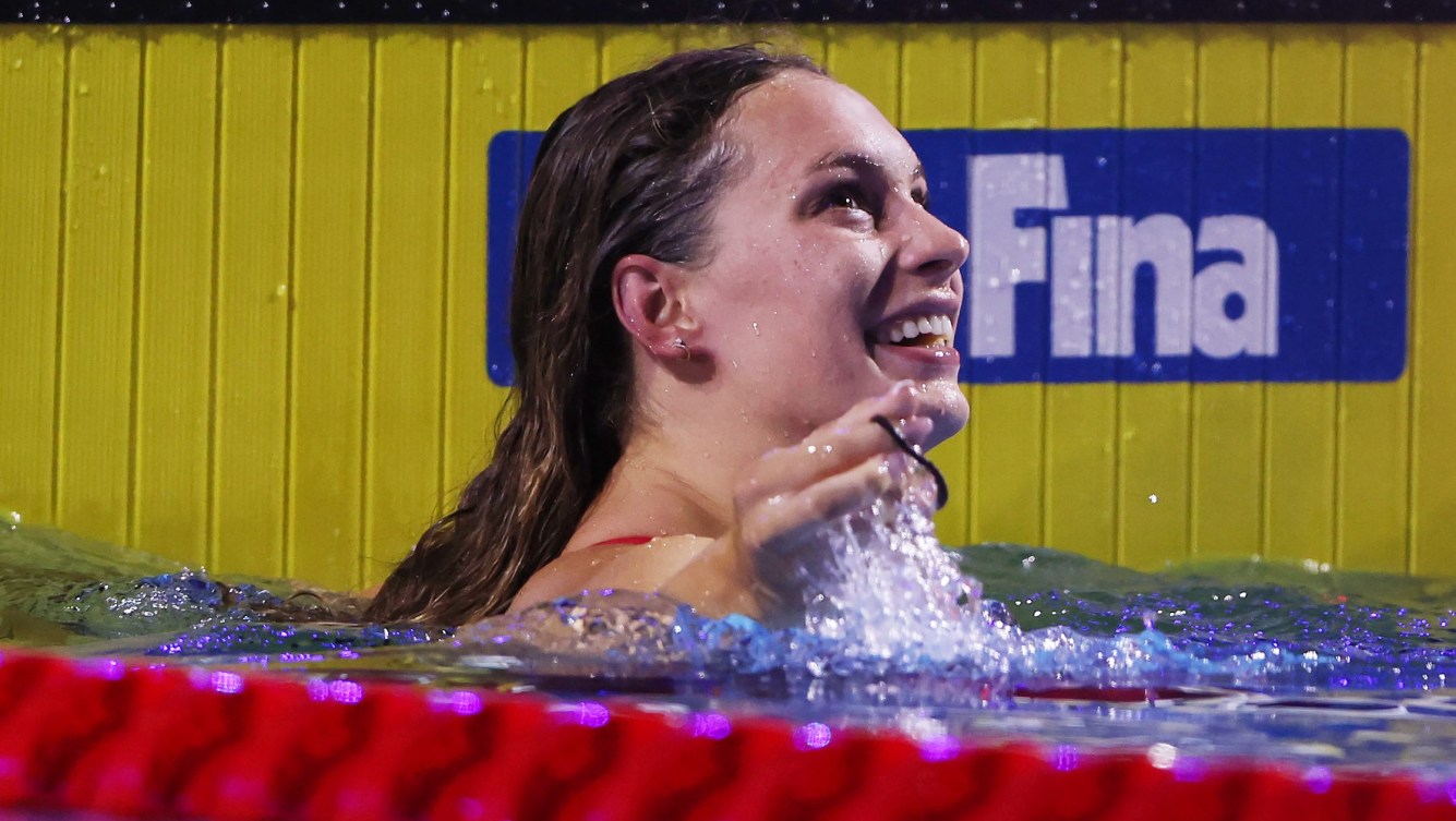 Penny Oleksiak smiles as she looks to the scoreboard while in the pool by the wall